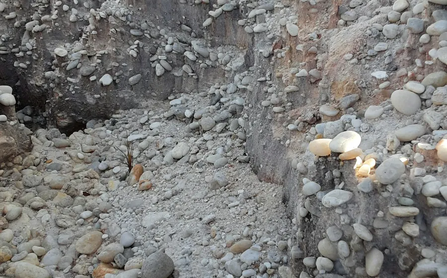 Excavación que muestra capas de suelo con ripio y bolones