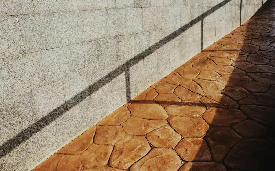 Pavimento de hormigón estampado color terracota junto a un muro