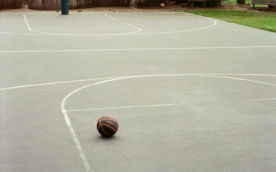 Cancha de hormigón con líneas pintadas y un balón de básquetbol