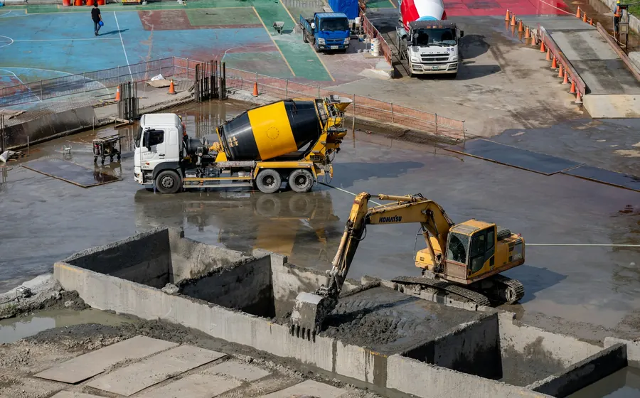 Camión mixer y excavadora trabajando en un patio de obra pavimentado