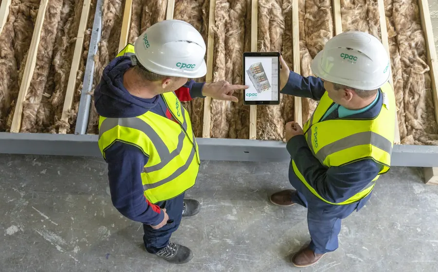 Dos trabajadores con casco revisando planos en una tableta en obra