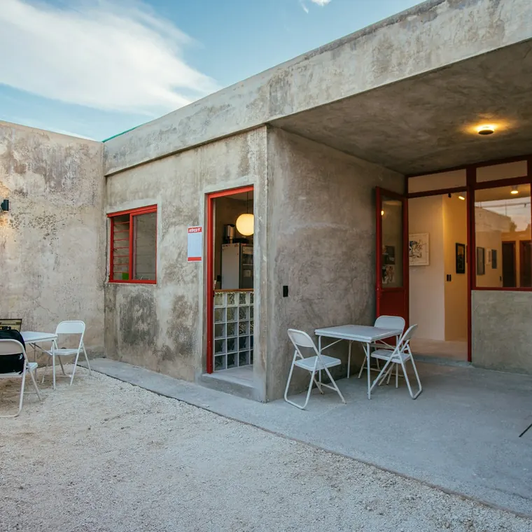 Patio de hormigón con mesas y sillas junto a una casa