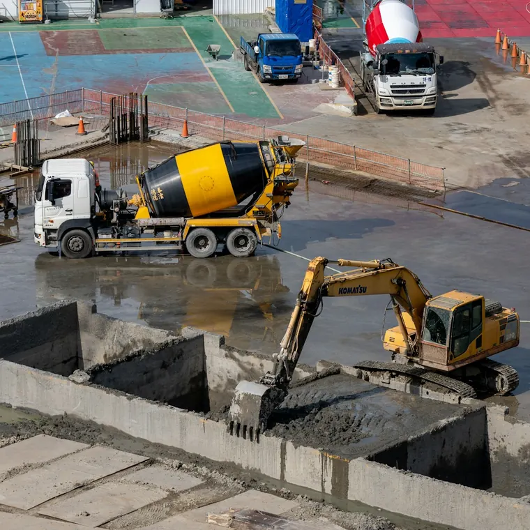 Camión mixer y excavadora trabajando en un patio de obra pavimentado